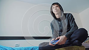 Young teen and joystick man hooded sweater absorbed In online video game. boy teenager in the hood playing video games