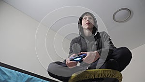 Young teen and joystick man hooded sweater absorbed In online video game. boy teenager in the hood playing video games