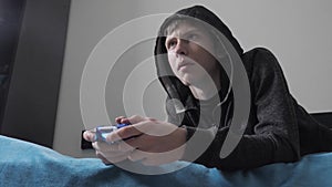 Young teen and joystick man hooded sweater absorbed In online video game. boy teenager lifestyle in the hood playing