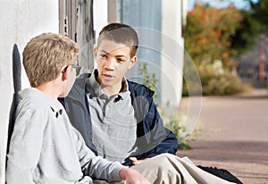 Young teen males talking to friend outside