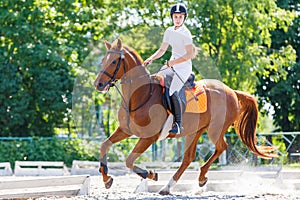 Young teen rider girl on show jumping competition