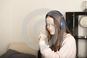 Young teen student girl listening to music at home with headphones, dancing, singing along