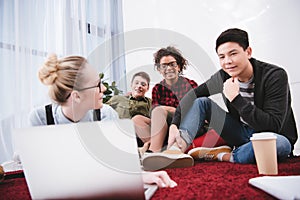 young teen students lying on carpet with notebooks and looking