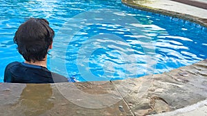 Young teen in swimming pool from behind with copy space.