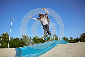 Young teen wearing inline skates doing balancing stunt at skateboard park