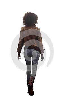 young teen woman walking away. African american woman wearing a brown leather jacket and light jean pants and boots.