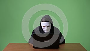 Young teenage boy computer hacker against green background