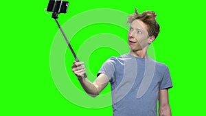 Young teenage boy taking selfie with selfie stick.