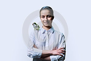 Young teenage female with green pet parrot, on white background photo