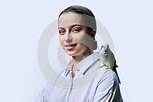 Young teenage female with green pet parrot, on white background photo