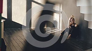 Young teenage girl dancer is suffering after loss casting sits on floor in dance studio indoors