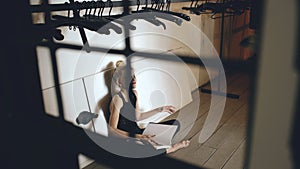 Young teenage girl dancer crying and tearing book sits on floor in hall indoors