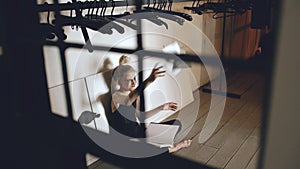 Young teenage girl dancer crying and tearing book sits on floor in hall indoors