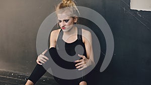 Young teenage girl dancer is very angry and suffering after loss casting sits on floor in dance studio indoors