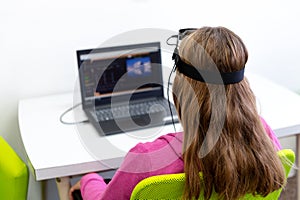 Young teenage girl during EEG neurofeedback session. Electroencephalography concept. Back view.