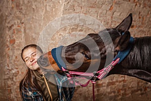 Young teenage girl equestrian kissing her chestnut horse