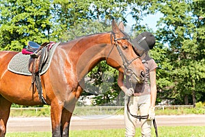 Young teenage girl equestrian kissing her favorite chestnut horse