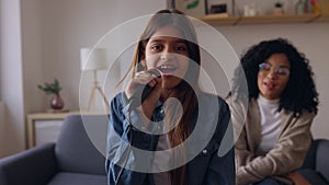 Young teenage girl having fun playing karaoke with her mum at home.