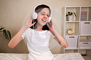 A young teenage girl with headphones listens to music