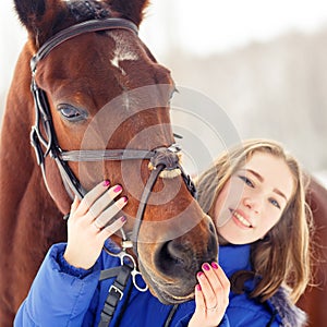 Young teenage girl with her horse in winter park