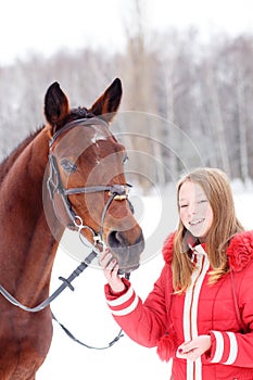 Young teenage girl with her horse in winter park