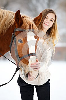 Young teenage girl with horse in winter park