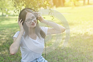 Young teenage girl listening music with headphones and smart phone in the park, summer portrait