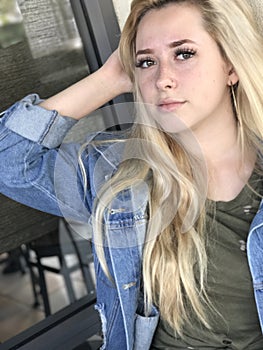 Young teenage girl with long blonde hair and denim jacket