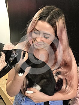 Young teenage girl with long hair holding a pet black cat