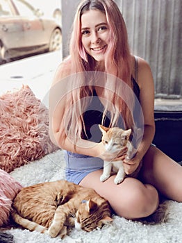 Young teenage girl with long hair holding pet cats