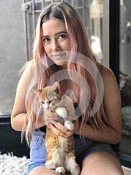 Young teenage girl with long hair holding pet cats