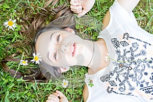 Young teenage girl lying in grass and flowers with stretched hand