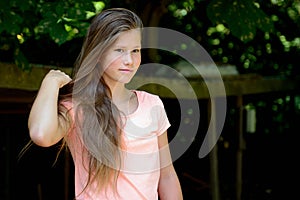 Young teenage girl in the park with calm facial expression.