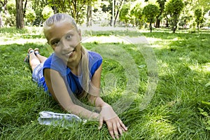 Young teenage girl in a park lying on the green meadow