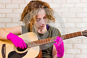 A young teenage girl plays the guitar in rubber gloves and learns chords or a song. Getting out of quarantine