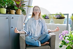 Young teenage girl relaxing meditating at home with her eyes closed in lotus position