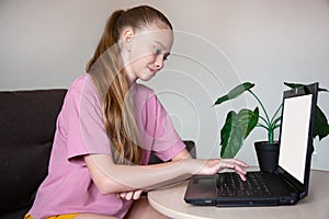 Young teenage girl sitting at laptop at home online