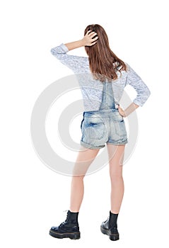 Young teenage girl standing and looking on something. Back pose, full length