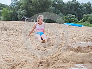 Young teenage girl in swimsuit sitting on sand at beach exotic resort