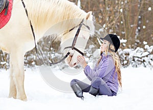 Young teenage girl with white horse in winter park