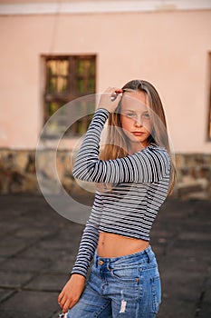 Young teenage poses to photographer. blonde girl in jeans and blouse