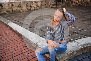 Young teenage poses to photographer. blonde girl in jeans and blouse