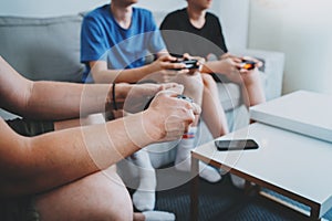 Young teenage sitting on a sofa in living room and playing video games. Family relaxing time at home concept. Closeup.