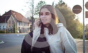 A young teenage woman is waiting for a bus at a bus stop early in the morning.