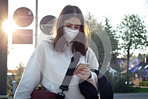 A young teenage woman is waiting for a bus at a bus stop early in the morning.