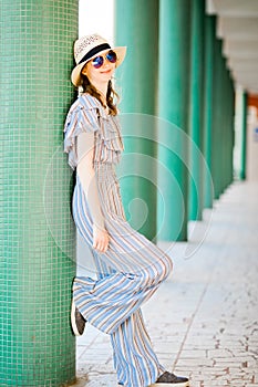 Young teenaged girl in jumpsuit dress posing at colonnade