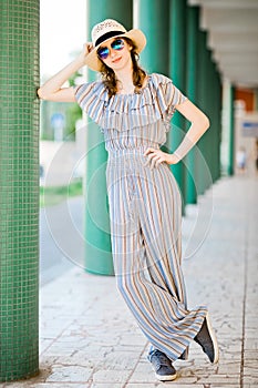 Young teenaged girl in jumpsuit dress posing at colonnade