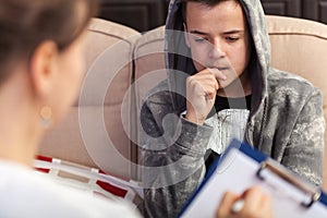 Young teenager boy at counseling - biting nails immersed in thoughts, close up