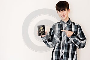Young teenager boy holding Bahamas passport looking positive and happy standing and smiling with a confident smile against white