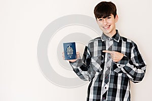 Young teenager boy holding Canada passport looking positive and happy standing and smiling with a confident smile against white